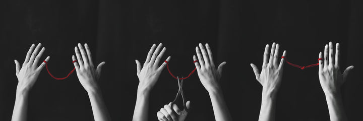 Hands with a red string symbolizing centering and re-centering during bondage meditation. 