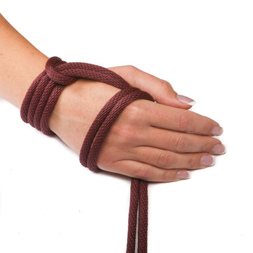 Knotty Desires burgundy polypropylene bondage rope knotted around a hand.